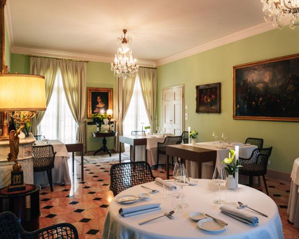 Ristorante elegante con lampadari, quadri e tavoli apparecchiati.